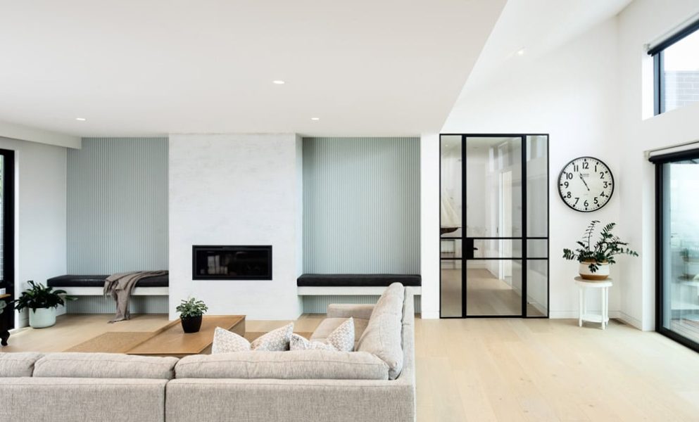 A living space by home builders in Melbourne — features pale wooden floors and minimalist Scandinavian decor.