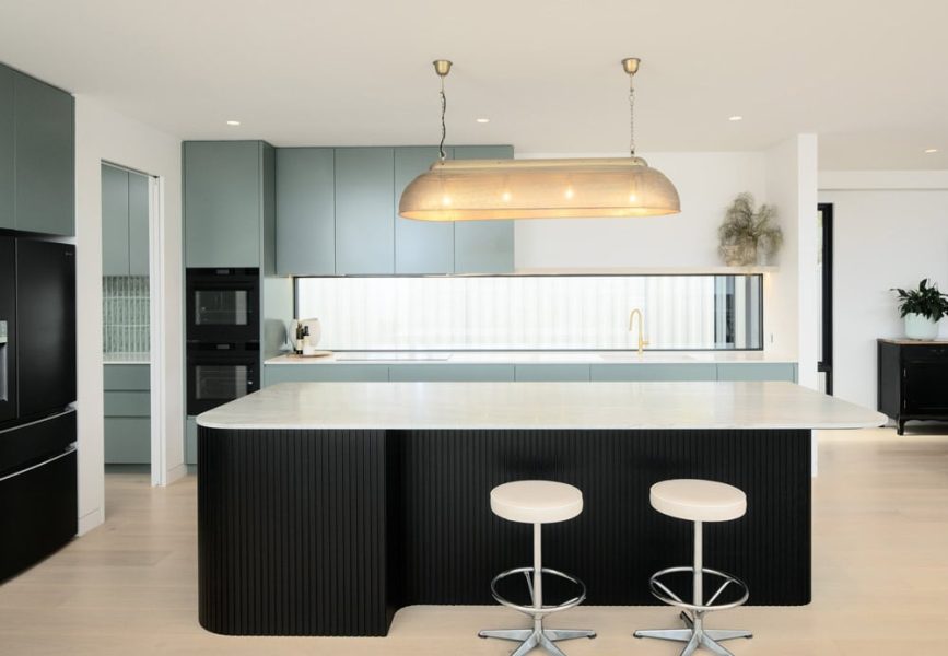 A stylish kitchen home renovation in Melbourne — showcases a ribbed matte-black island topped with white stone.