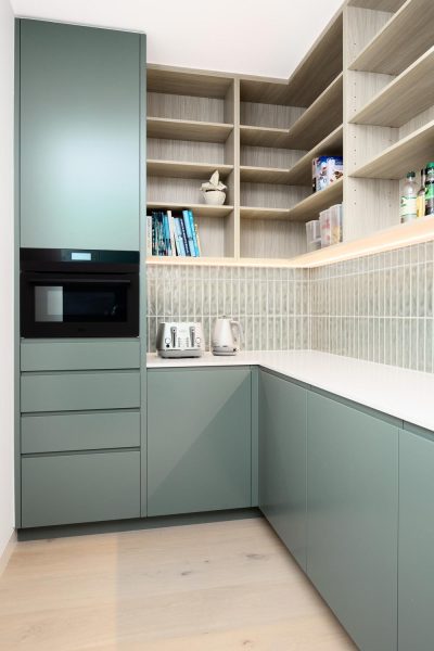 A butler’s pantry home renovation in Melbourne — features sage-green cabinetry with an integrated oven and timber shelving.