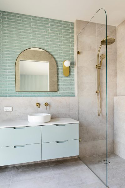 An elegant bath ensuite bathroom by home builders in Melbourne — features frameless glass fitted with matte-brass fixtures.
