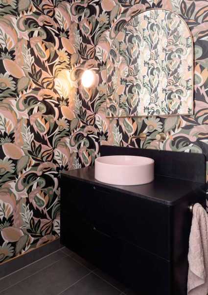 A powder room crafted during home renovations in Melbourne — showcases floral wallpaper in dusty pink, sage and charcoal.