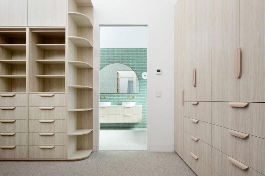 A walk-through dressing room home renovation in Melbourne — features pale timber cabinetry with curved corner shelves.
