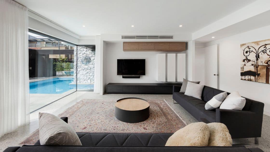 A living room by Spacemaker overlooking a pool area demonstrates ways to reduce a home's carbon footprint through design.