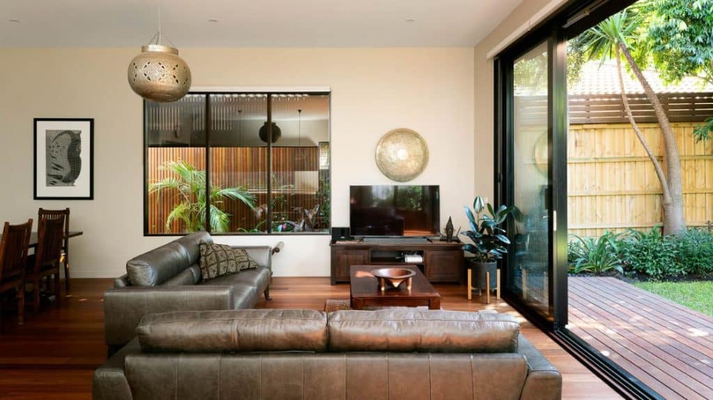 A modern living room renovation by Spacemaker features wooden flooring, warm furnishings, and a beautiful outdoor area.